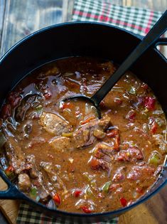 a pot filled with stew on top of a wooden cutting board next to a knife