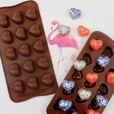 chocolates and candy heart shaped candies are sitting next to an ice tray with flamingos on it