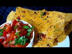 some food is on a white plate with a bowl of salsa and tortilla