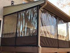 a screened porch in front of a house with siding on the side and an awning over it