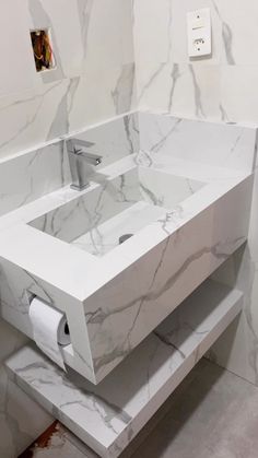 a white bathroom sink sitting next to a toilet paper dispenser on a counter