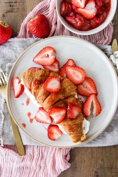 a white plate topped with pastry covered in strawberries