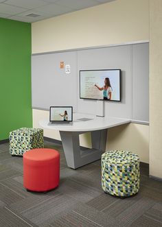 an office cubicle with tables, stools and pictures on the wall