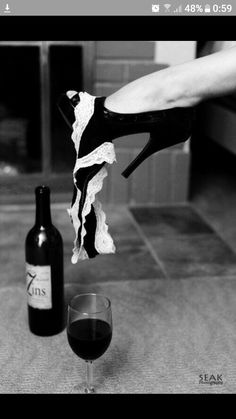 a woman's shoe is dangling from a wine glass next to a black and white photo