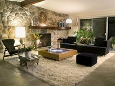 a living room filled with furniture and a fire place next to a wall mounted stone fireplace