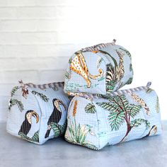 three pieces of blue fabric with animals and trees on them, sitting next to each other in front of a white brick wall