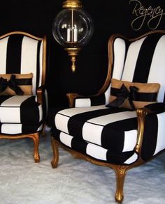 two black and white striped chairs sitting next to each other in front of a lamp