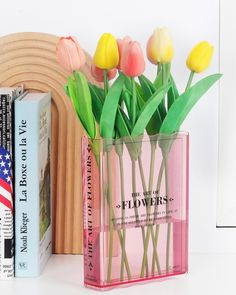 flowers are in a pink vase next to books