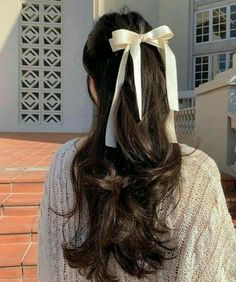 the back of a woman's head with a white bow in her hair,