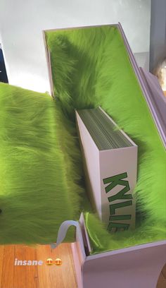 an open box sitting on top of a green fur covered bed cover next to a pair of sunglasses