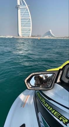 the reflection of a boat on the water in front of a tall building