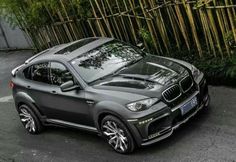 a grey bmw suv parked in front of a bamboo fence