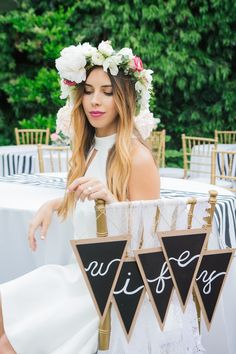 a woman wearing a flower crown holding up a sign