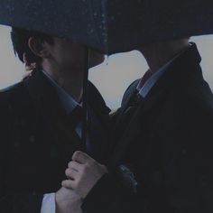 two people kissing under an umbrella in the rain