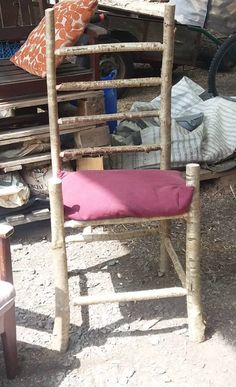 a chair made out of sticks with a pink cushion on it and other items in the background