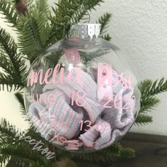 a glass ornament with baby's names and mittens in the shape of a ball