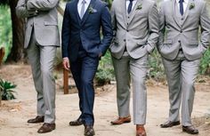 a group of men in suits standing next to each other on a dirt road with trees in the background