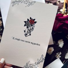 a woman holding up a card that says, a single rose can be my garden