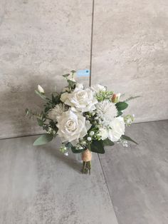 a bouquet of white flowers sitting on top of a table next to a wall with a price tag