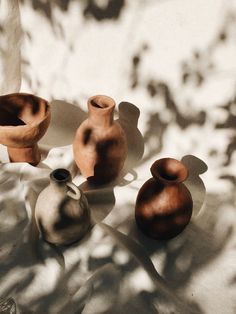 three vases sitting on top of a table next to each other in front of a white wall