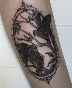 a black and white photo of a bat in a frame tattoo on the right leg