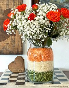 a vase filled with flowers sitting on top of a checkered table cloth next to a wooden heart