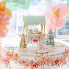 a table topped with lots of balloons and cake next to a small house on top of it