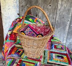 a wicker basket sitting on top of a quilt covered table cloth next to a wooden wall