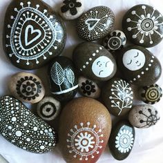 some rocks with different designs on them sitting on a white sheet and one has a heart painted on it