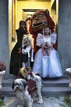 three children and two dogs are dressed up in costumes on the front steps of a house