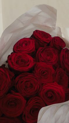 a bouquet of red roses is wrapped in white paper and ready to be placed on the table