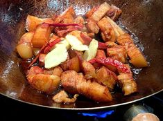 some food is cooking in a wok on the stove with other items around it