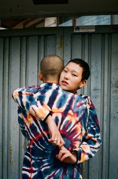 a young boy is hugging an older man's back in front of a metal wall