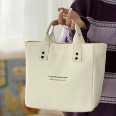 a woman holding a white bag with words on it