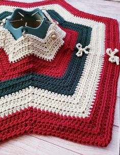 a crocheted blanket on top of a wooden floor with scissors and other items