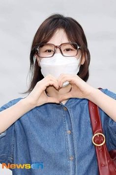 a woman wearing glasses making a heart shape with her hands in front of her face