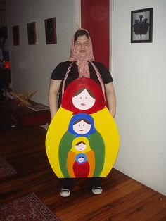 a woman standing in a room holding a cardboard cutout of three people on each side of her face