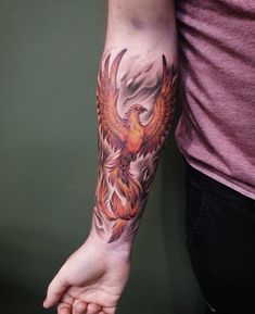 a person with a tattoo on their arm and hand holding an eagle in the air