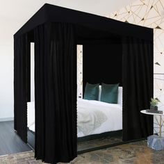 a black canopy bed with white sheets and pillows