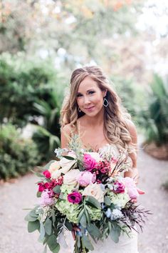 a woman holding a large bouquet of flowers in her hand and smiling at the camera