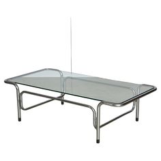 Italian vintage coffee table, expertly crafted with stunning, bold chromed curves that are sure to captivate and impress. The low profile, glass top, and elongated shape of this piece create a sense of fluidity and movement, adding a touch of sophistication and elegance to any living space. Elevate your home decor with this unique and timeless statement piece that effortlessly combines form and function. Chrome And Glass Coffee Table, Vintage Coffee Table, Low Coffee Table, Italian Mid Century Modern, Coffee Cocktails, Coffee And Cocktail Tables, Coffee Table Vintage, Glass Coffee Table, The Low