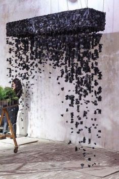 a woman is standing in front of a sculpture made out of black rocks and sticks