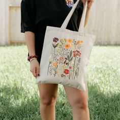 "Embrace everyday elegance with our Wildflower Watercolor Tote Bag, crafted from 100% cotton canvas for durability and style. Measuring at a perfect 15\" x 16\", this bag boasts vibrant colors to showcase your favorite designs while ensuring lasting quality for years to come. Designed with convenience in mind, our tote features sturdy 20\" handles made from the same durable canvas, ensuring easy carrying whether you're out for a quick errand or a week-long shopping spree. Its heavy fabric (12 oz/yd² or 406.9 g/m²) construction guarantees reliability and resilience, making it your go-to accessory for every adventure. Available in natural and black colors to suit your aesthetic preferences, our tote bag is adorned with a sewn-in label, a symbol of our dedication to quality and sustainability Birthday Gift Bags, Bags Aesthetic, Floral Gifts, Pressed Flowers, Canvas Tote, Gift Bag, Cotton Canvas, Wild Flowers, Vibrant Colors