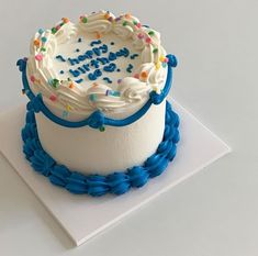 a white cake with blue icing and sprinkles on it's top