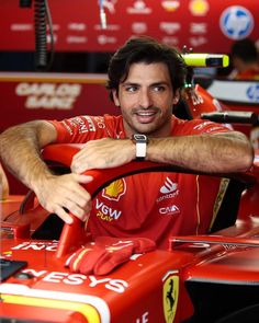 a man sitting in a race car with his arm resting on the steering wheel