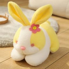 a yellow stuffed rabbit sitting on top of a wooden floor next to a white rug