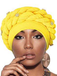 a woman wearing a yellow turban with jewels on her head and finger in her mouth