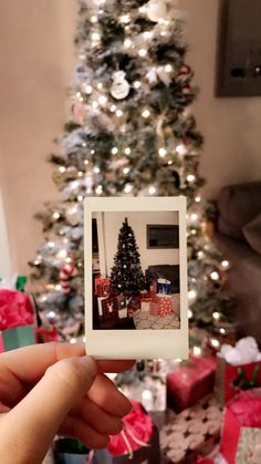 a person holding up a polaroid in front of a christmas tree