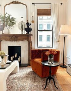 a living room filled with furniture and a fire place in front of a mirror on the wall