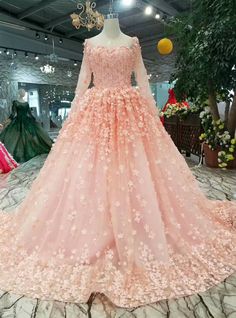 a pink wedding dress with flowers on the skirt and long sleeves, in a store